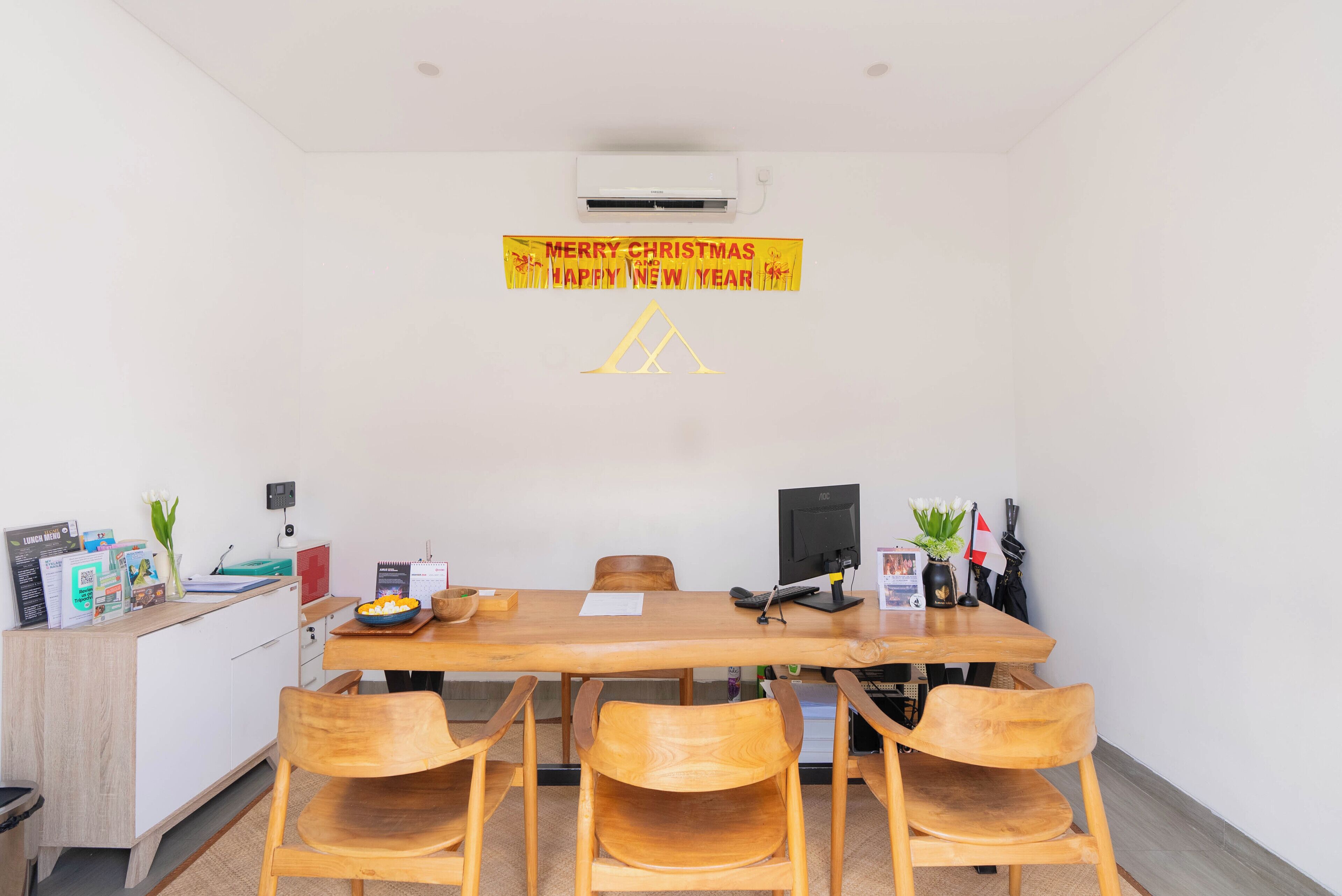 A conference room with a wooden table, four chairs, a whiteboard, and a banner on the wall.