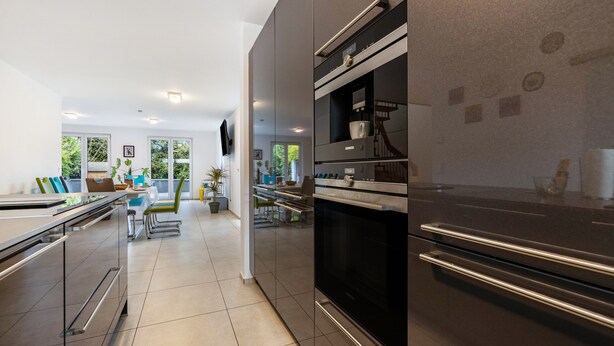 Una cocina moderna con electrodomésticos de acero inoxidable, un comedor con vistas y un amplio ventanal.