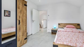 Une chambre à coucher comprenant un lit, une armoire, une table de chevet et une étagère fixée au mur.