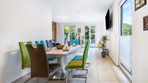 Un comedor moderno con una mesa larga, sillas y un televisor.