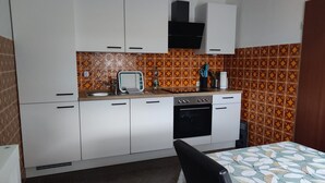 A compact kitchen with white cabinets, a stove, and a microwave. - Apartment 'Buedinger Weg' with Wi-Fi (Gründau)