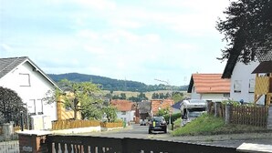 A residential street with houses, a gated entrance, and a car parked on the road. - Apartment 'Buedinger Weg' with Wi-Fi (Gründau)