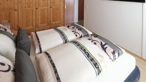 A bedroom with a wooden wardrobe, a flat-screen TV, and a bed with patterned bedding. - Apartment 'Buedinger Weg' with Wi-Fi (Gründau)