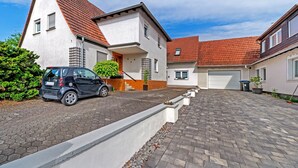 Ein zweistöckiges Haus mit rotem Ziegeldach, einem Auto auf der Auffahrt und einem gepflasterten Weg.