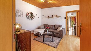 Ein Wohnzimmer mit Holzboden, einem braunen Sofa, einem Couchtisch mit einer Vase und einem Holzschrank.