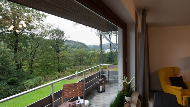 Ein Balkon mit Holztisch, Stühlen und Topfpflanzen.