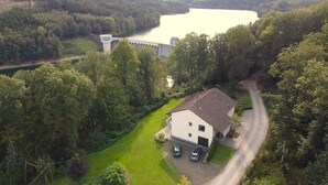 Ein weißes Gebäude mit einem geneigten Dach und einer gepflasterten Auffahrt, vor der zwei Autos geparkt sind.