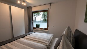 Ein Schlafzimmer mit einem Bett, einem Fenster mit Blick, einem Heizkörper und einer Zimmerpflanze.