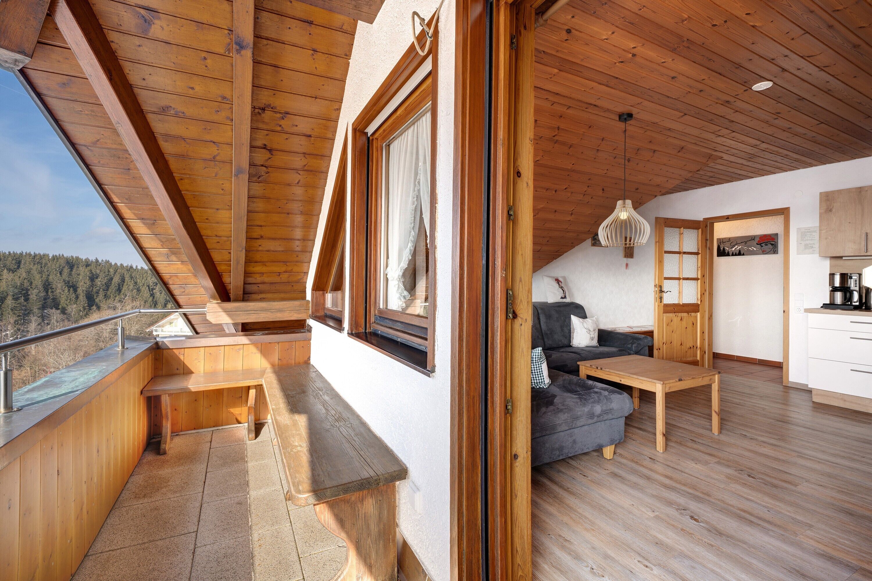Un intérieur en bois avec un balcon, un canapé, une table et un coin cuisine.