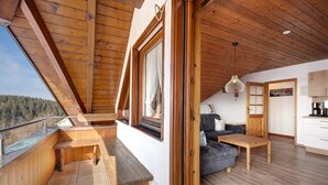 Ein Holzinnenraum mit Balkon, einer Couch, einem Tisch und einer Küchenzeile.