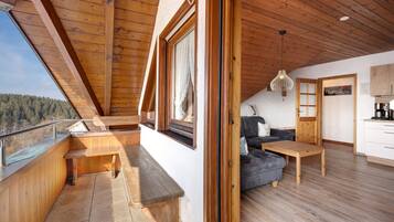 Un intérieur en bois avec un balcon, un canapé, une table et un coin cuisine.