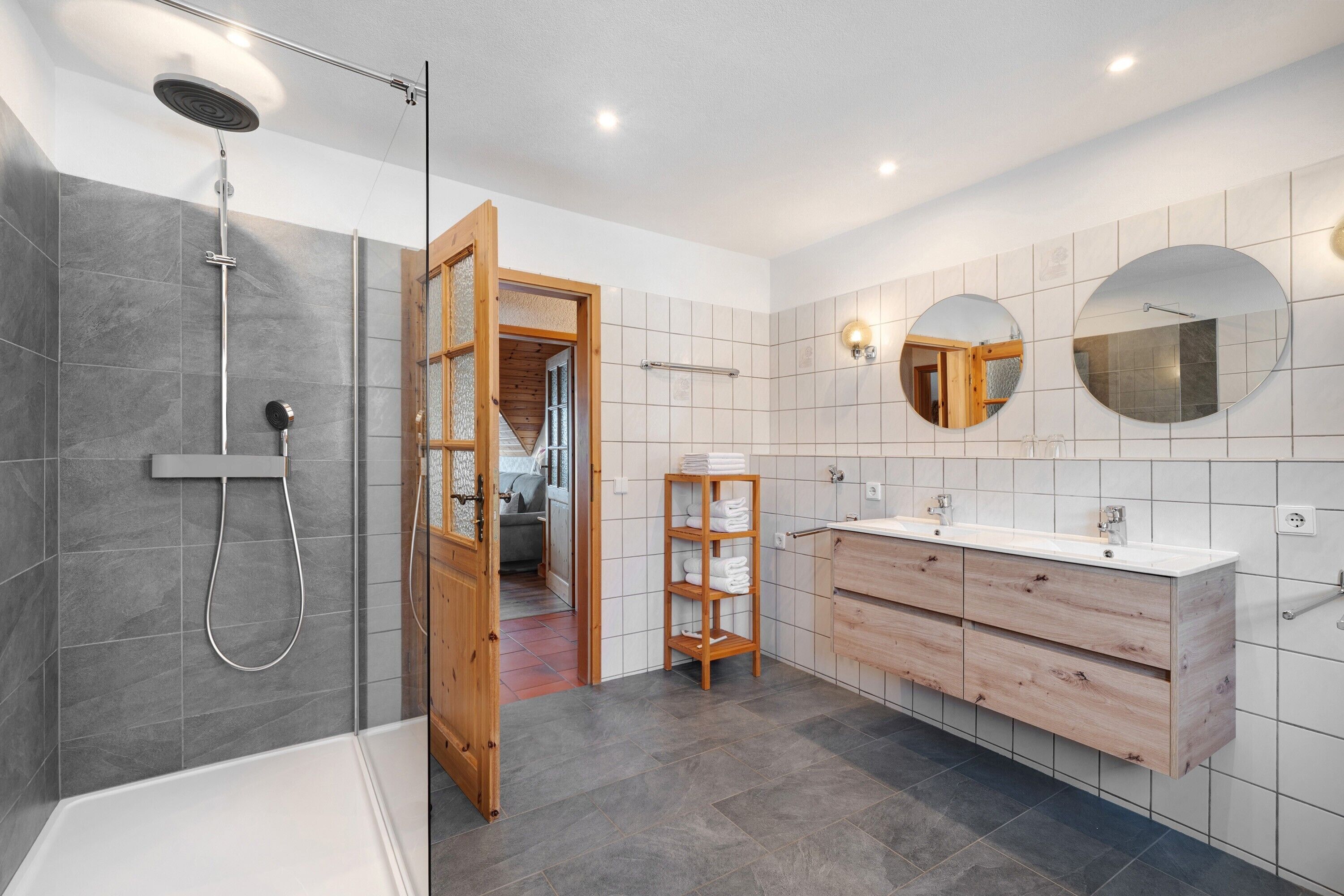 A modern bathroom with a shower, vanity, and a mirror.