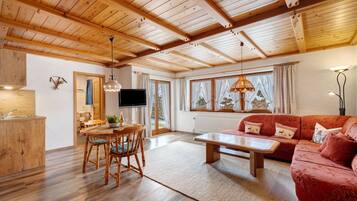 Ein Holzinterieur mit Essbereich, einer Couch und einem Fernseher.