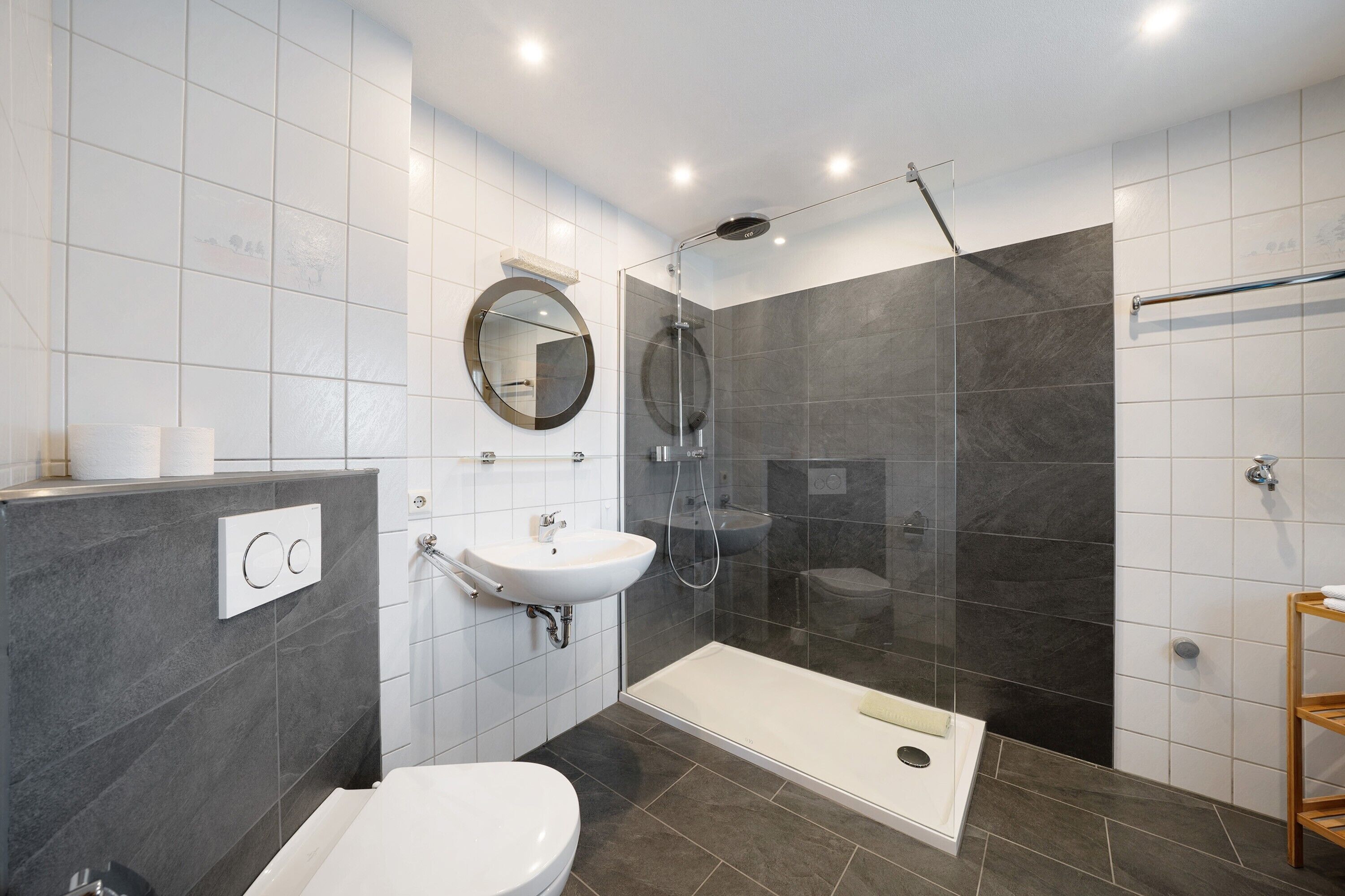 A modern bathroom with a toilet, sink, shower, and a glass-enclosed shower stall.