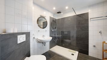 A modern bathroom with a toilet, sink, shower, and a glass-enclosed shower stall.
