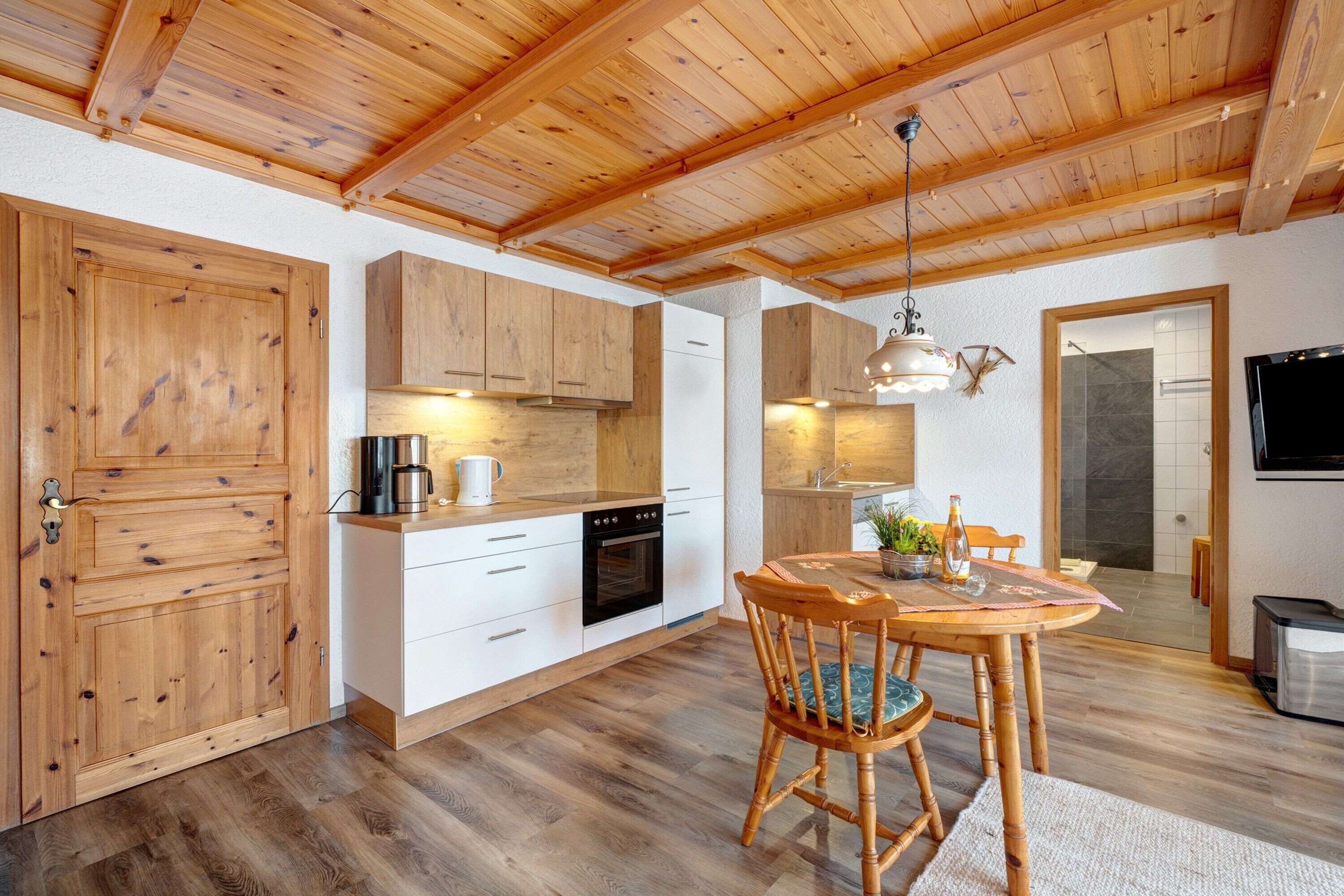 A kitchen with wooden cabinets, a dining table with chairs, and a hanging light fixture.