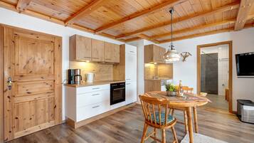A kitchen with wooden cabinets, a dining table with chairs, and a hanging light fixture.