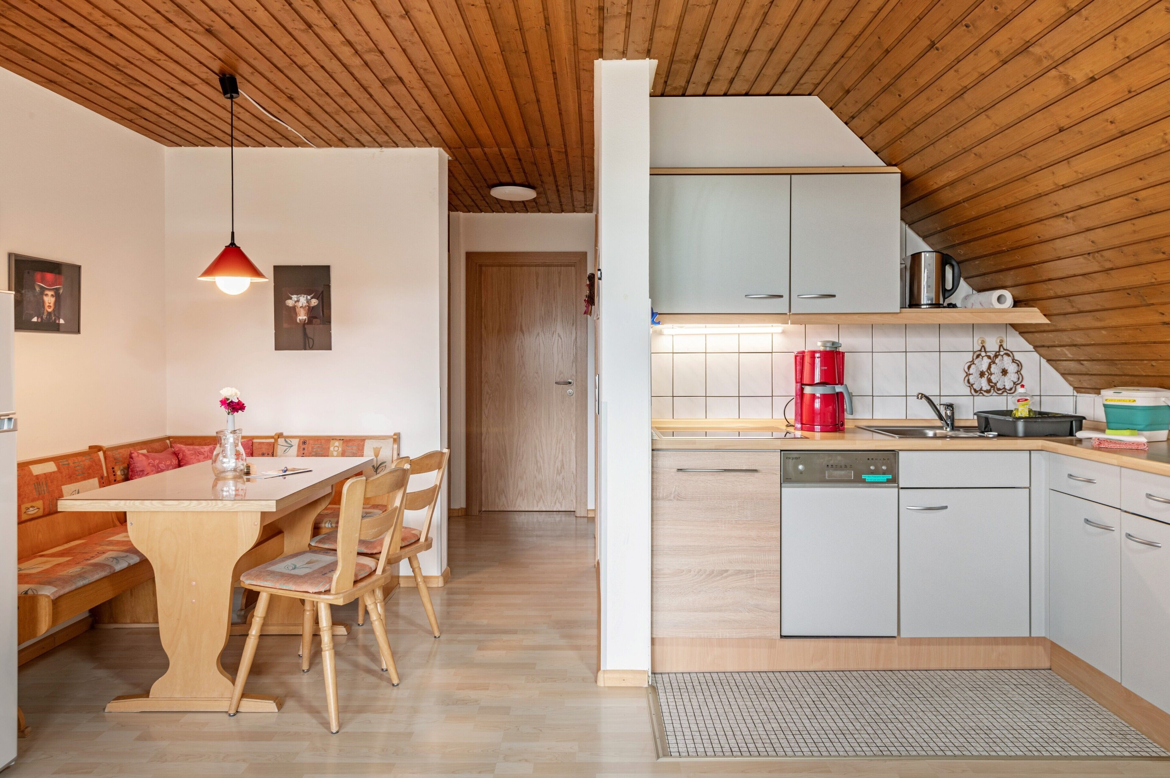 A modern kitchen with wooden cabinets, a red coffee maker, and a tiled backsplash.