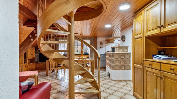 Un intérieur en bois avec un escalier en colimaçon, des meubles de rangement en bois et un coin repas.