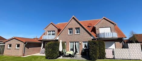 A two-story brick house with a red-tiled roof, a front porch, and a well-maintained lawn.