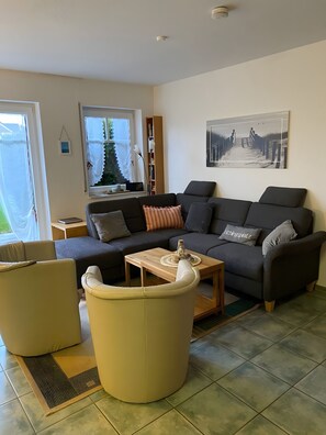 Un salon moderne comprenant un canapé, des fauteuils, une table basse, une bibliothèque et un tableau accroché au mur.