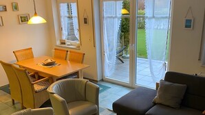 Ein Wohnzimmer mit einer Couch, Sesseln, einem Couchtisch und einem Essbereich mit Tisch und Stühlen.