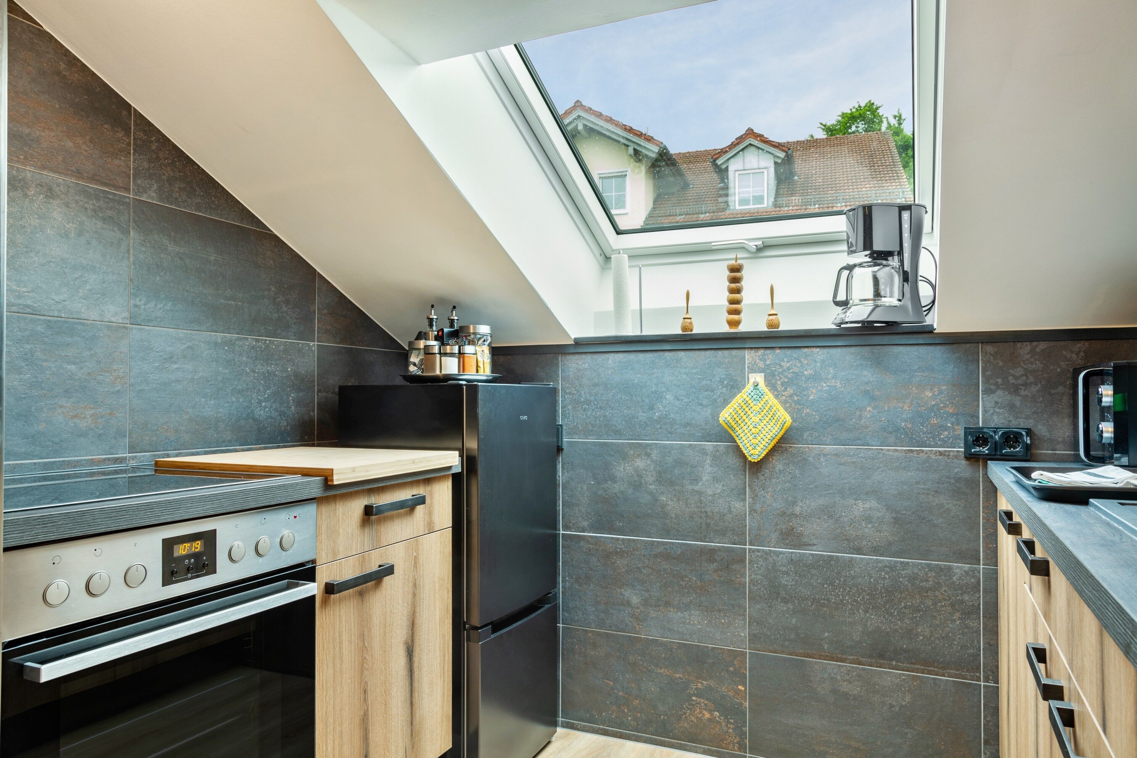 A modern kitchen with a skylight, a built-in oven, and a coffee maker.