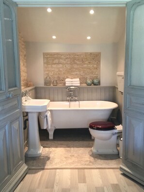 Bathroom features a bathtub, pedestal sink, and toilet with a wooden seat.