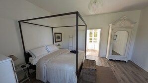 A four-poster bed with a white bedspread, a bedside table with a lamp, a wicker basket, and a large mirror on the wall. - Stylish Manor House, 6 Bed, Heated Outdoor Pool, Outdoor Kitchen, Sleeps 15 (Pouille)