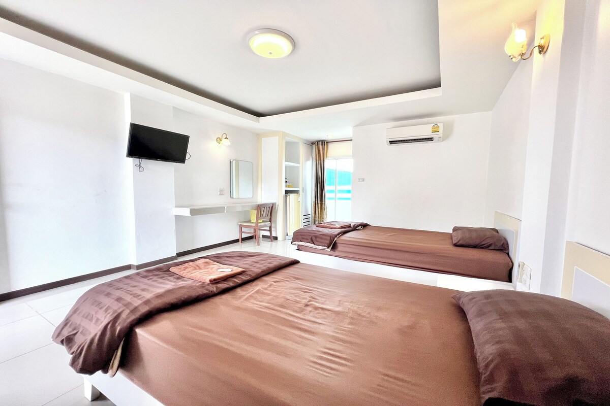 A hotel room with two beds, a TV, a desk, and a chair.