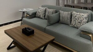 En moderne stue med en grå sofa, et rundt sofabord og et kaffebord.