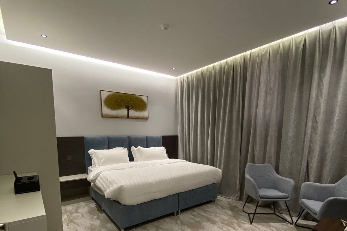 Een moderne hotelkamer met een groot bed, twee fauteuils, een bureau en een schilderij aan de muur.