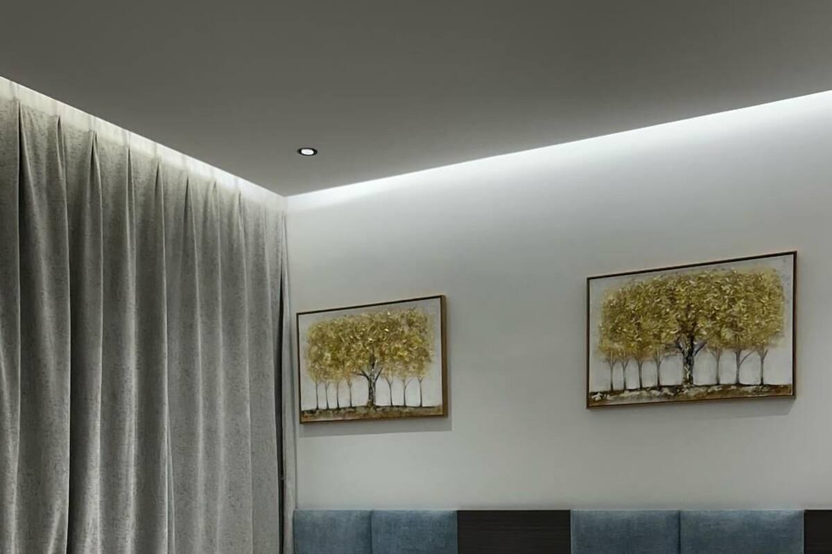 Een hotelkamer met twee bedden, grijze gordijnen en twee aan de muur hangende schilderijen van bomen.