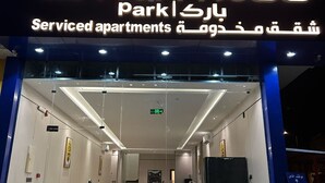 En bygning med et skilt, der viser "QIMAM Park Apartments" og "Serviced apartments".