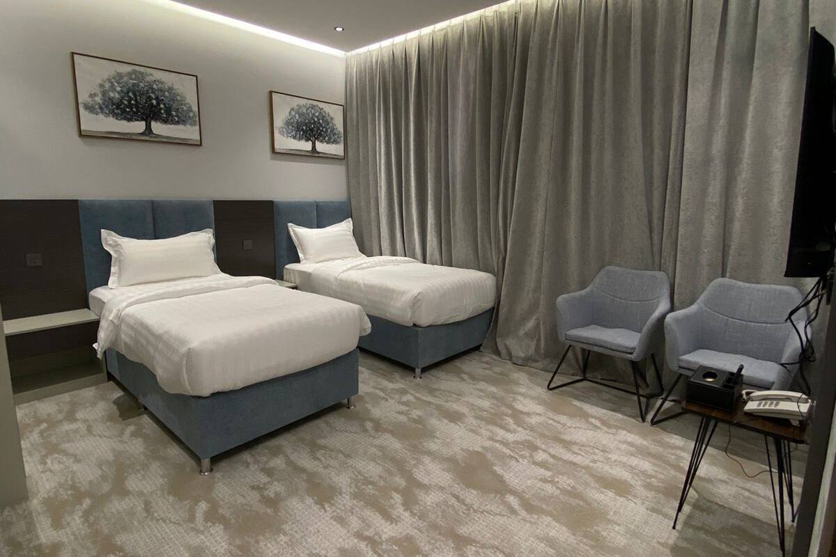 Hotelkamer met twee bedden, een zithoek met stoelen, een flatscreen televisie en kunstwerken aan de wanden.
