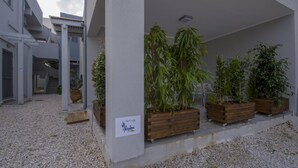 A building with a covered outdoor area, wooden planters with various plants, and a sign on the wall. - Alisahni Suite, Villa (Chania)