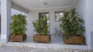 A building's exterior with three wooden planters on the ground floor, each containing a different type of plant. - Alisahni Suite, Villa (Chania)