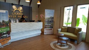 A hotel reception area with a marble counter, a sofa, and a small table. - Nemuru Grand Anyer Palazo (Anyer)
