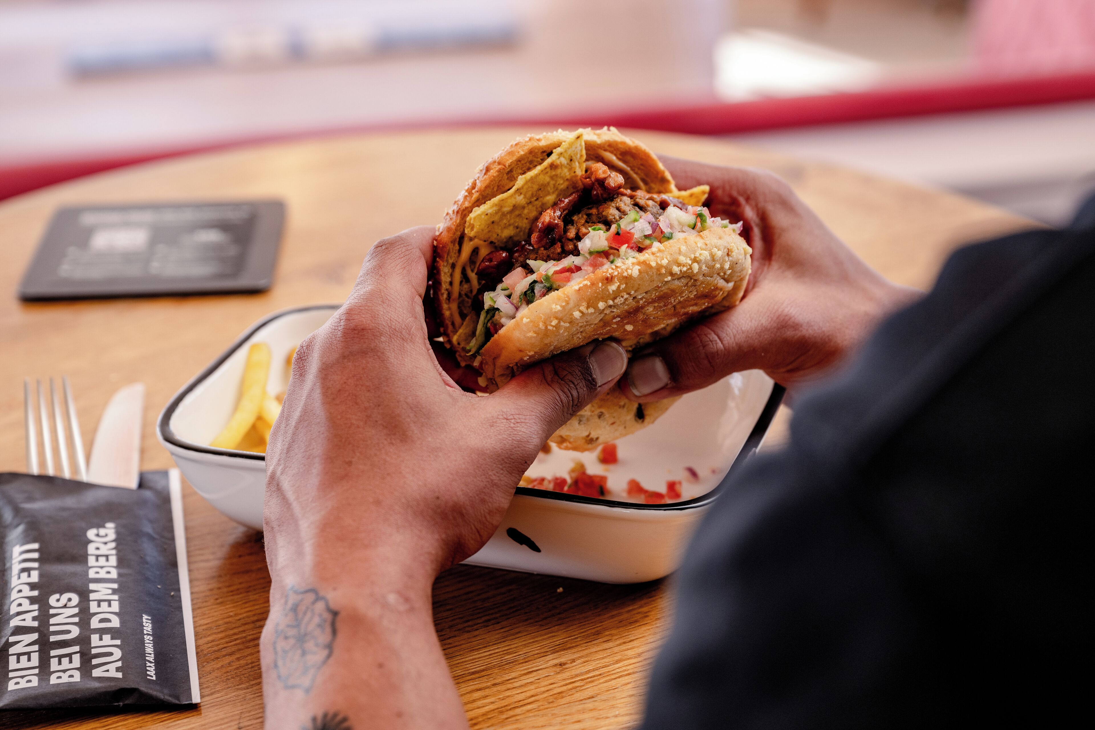 A person holding a wrapped sandwich with visible fillings.