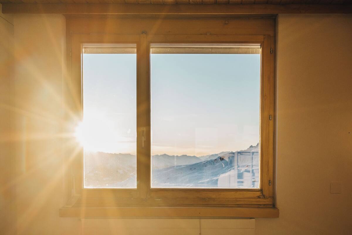 A room with a bed and a window overlooking a snowy landscape.