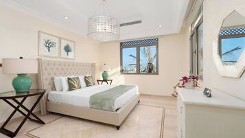 A bedroom with a large bed, a bedside table with a lamp, a window with a view, and a decorative mirror.