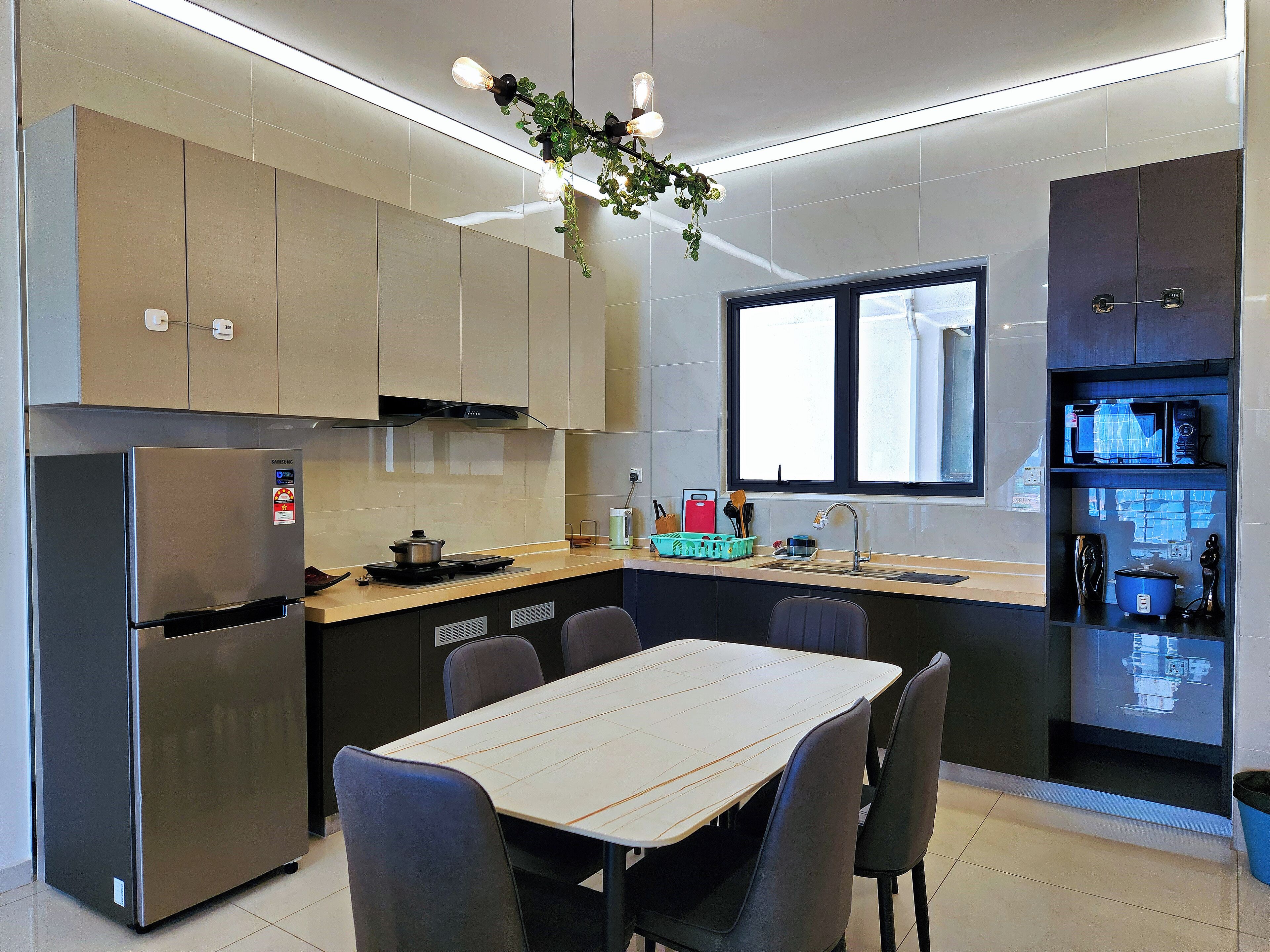 A modern kitchen with a built-in refrigerator, stove, and microwave. There is a dining table with chairs and a window providing natural light.