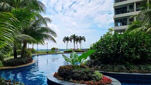 A pool area with palm trees and a view of a building in the background. - Country Garden Danga Bay by Widebed JB (Johor Bahru)