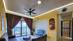 A modern living room with a sofa, a coffee table, a TV, and a ceiling fan. - Country Garden Danga Bay by Widebed JB (Johor Bahru)