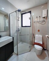 A modern bathroom with a glass-enclosed shower, a white sink, and a toilet.
