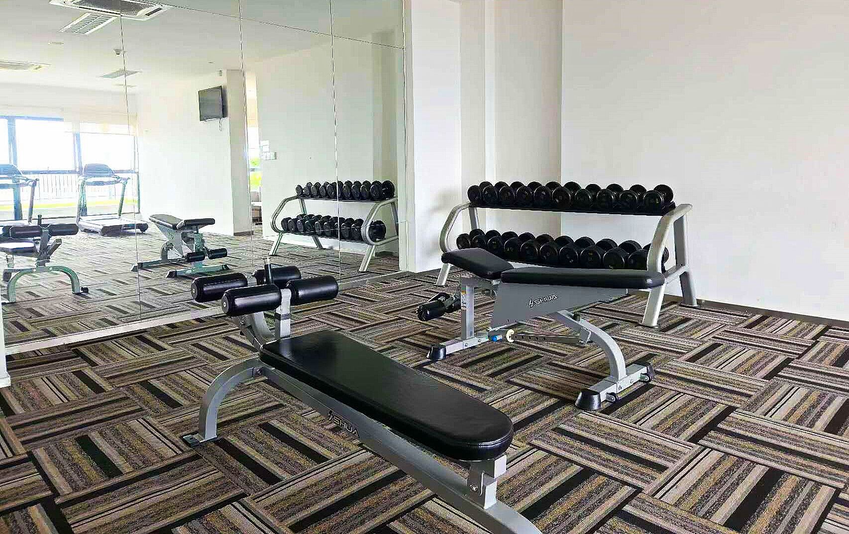 Une salle de sport équipée de matériel d’exercice, notamment des haltères et des bancs.