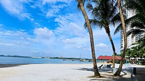 A beach with palm trees, a clear sky, and a view of the ocean. - Country Garden Danga Bay by Widebed JB (Johor Bahru)