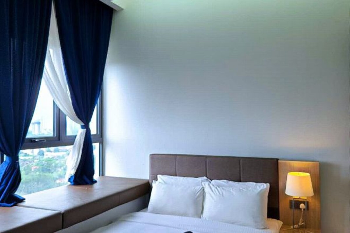 Una habitación de hotel con una cama, una mesita de noche con lámpara y una ventana con cortinas.