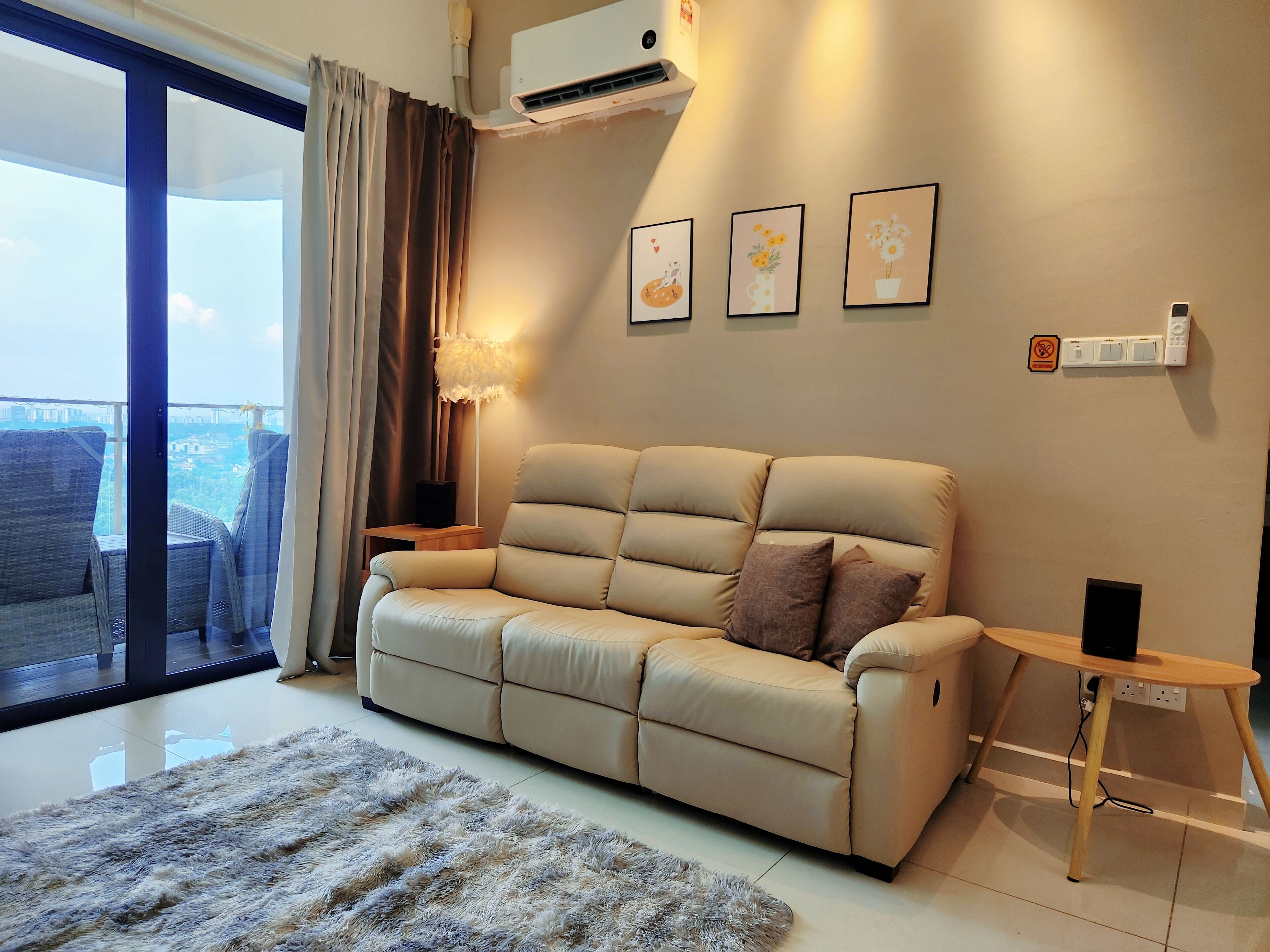 A modern living room with a beige sofa, a fluffy rug, and a city view through a large sliding glass door.