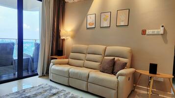 A modern living room with a beige sofa, a fluffy rug, and a city view through a large sliding glass door.